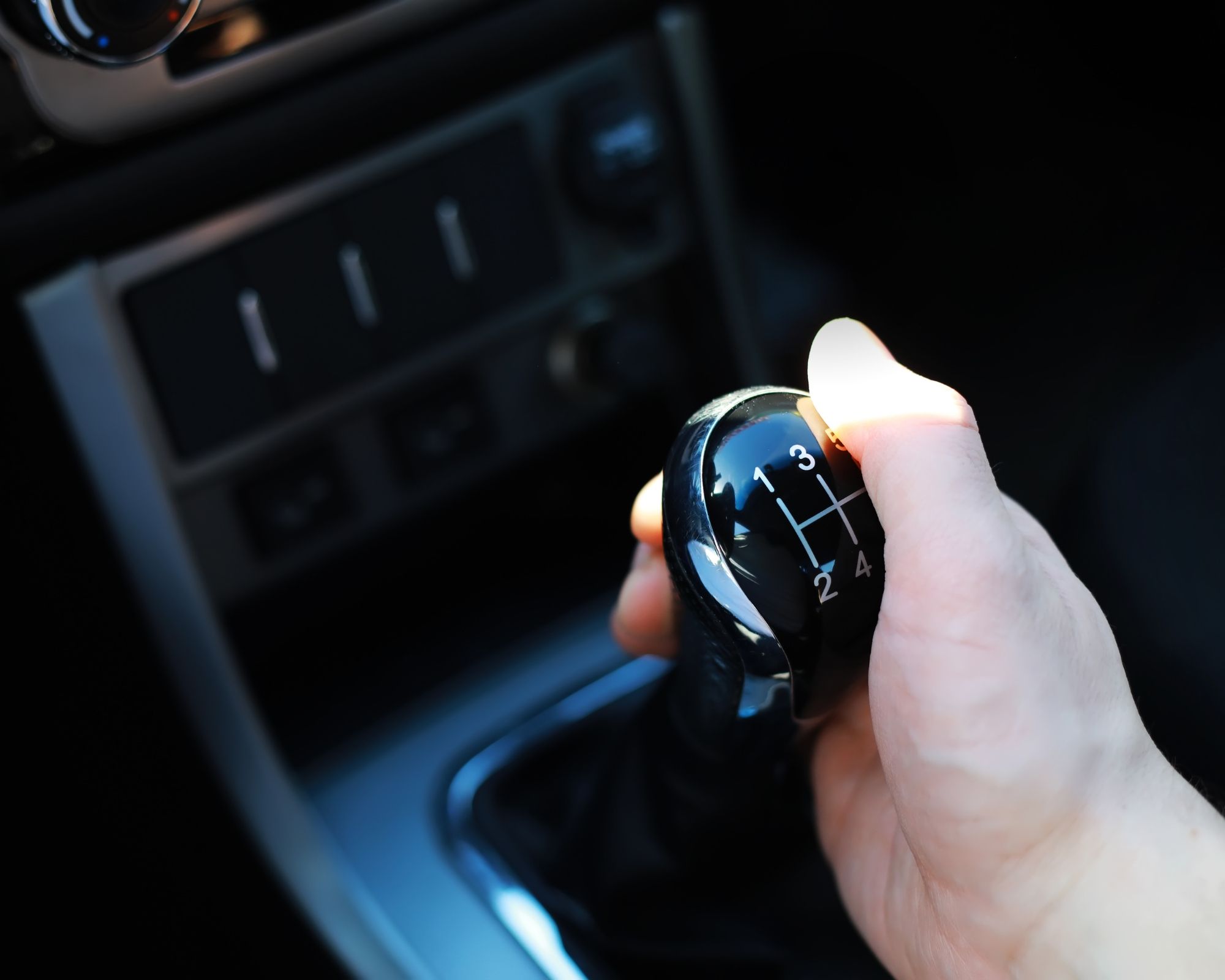 Hand op de versnellingspook van een handgeschakelde auto